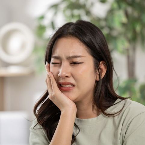 Woman holding her cheek where it is swollen
