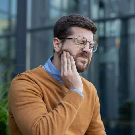 Man holding his jaw with a pained expression